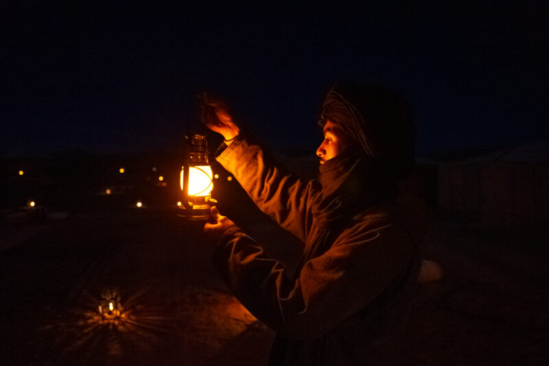 Desert Camp staff holding a lantern to illuminate the tents nearby